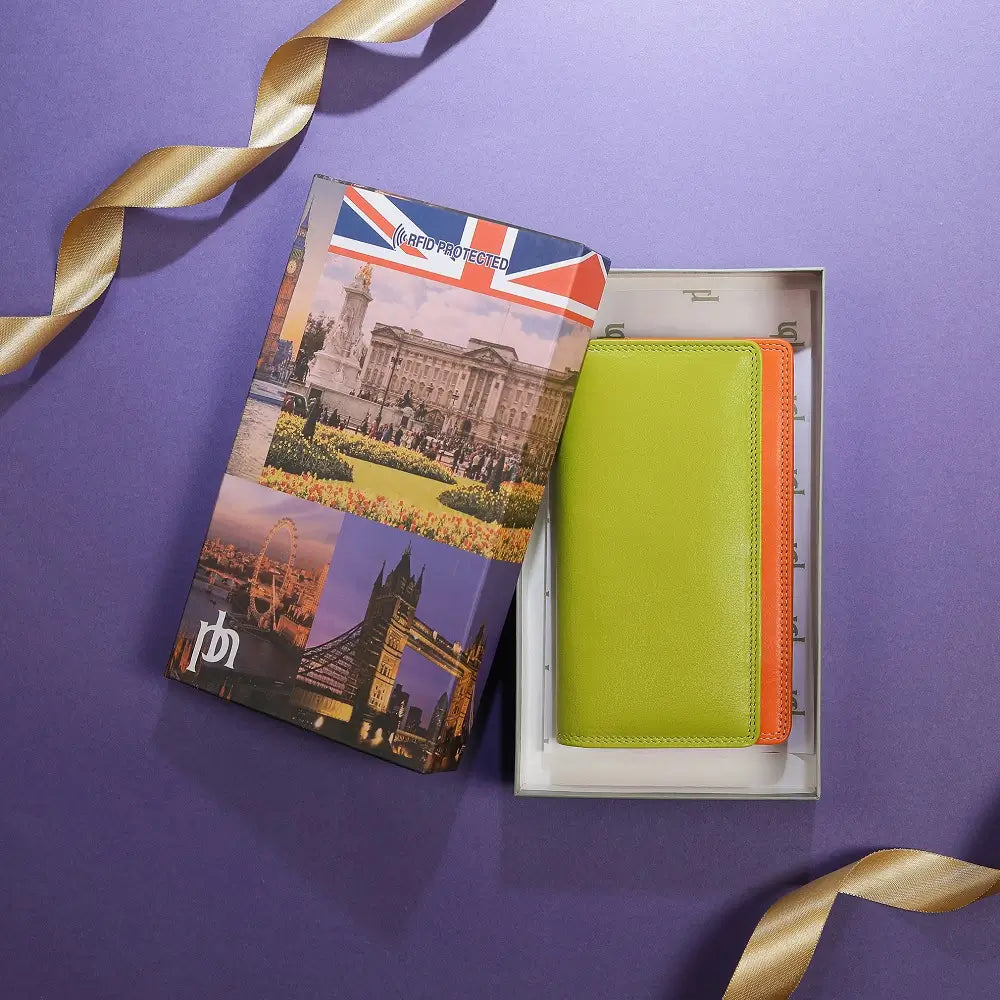 Green wallet with orange interior in a box, featuring a travel-themed passport cover on a purple background.
