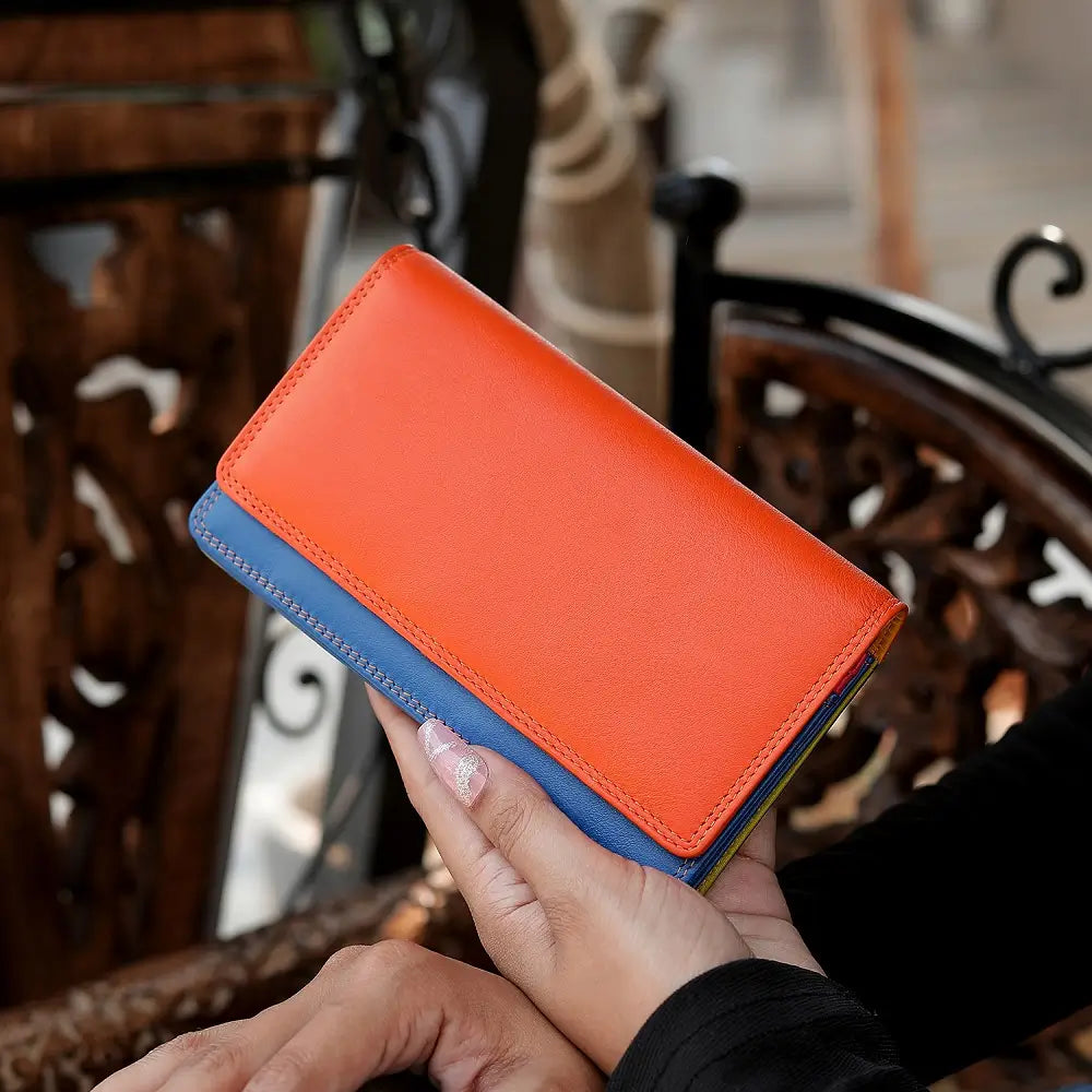 Person holding a orange wallet with a blurred indoor background