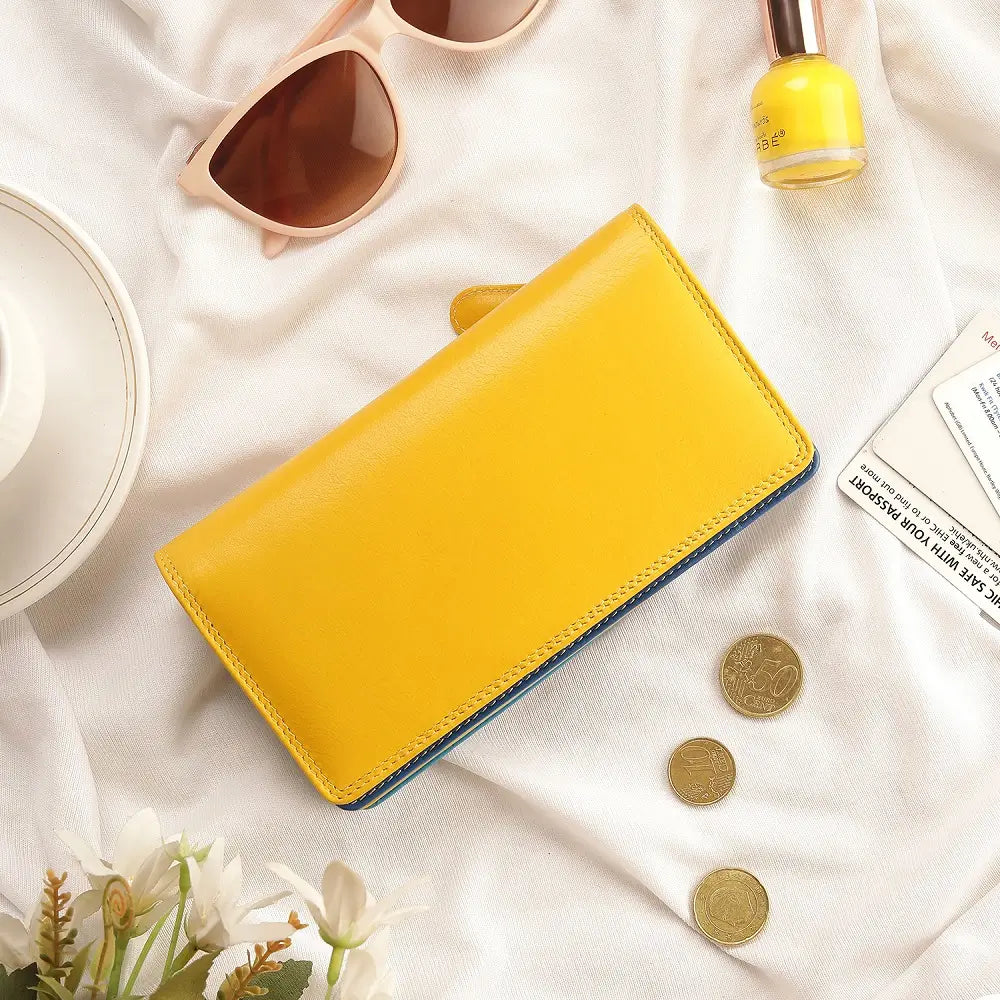 Yellow wallet on a white surface with sunglasses, coins, and a bottle of nail polish.