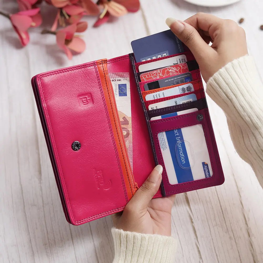 Person holding a Purple wallet on a wooden table.