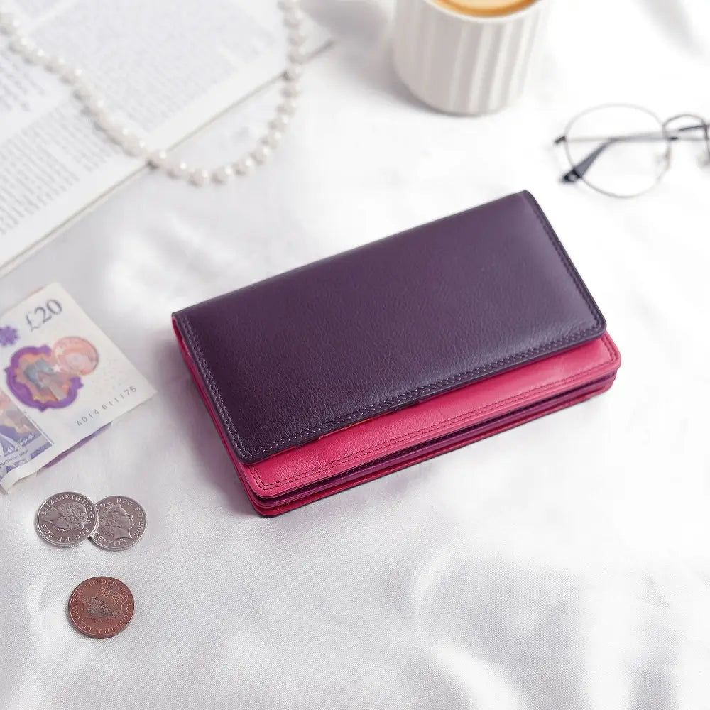 Purple wallet on a textured surface with coins and a banknote.