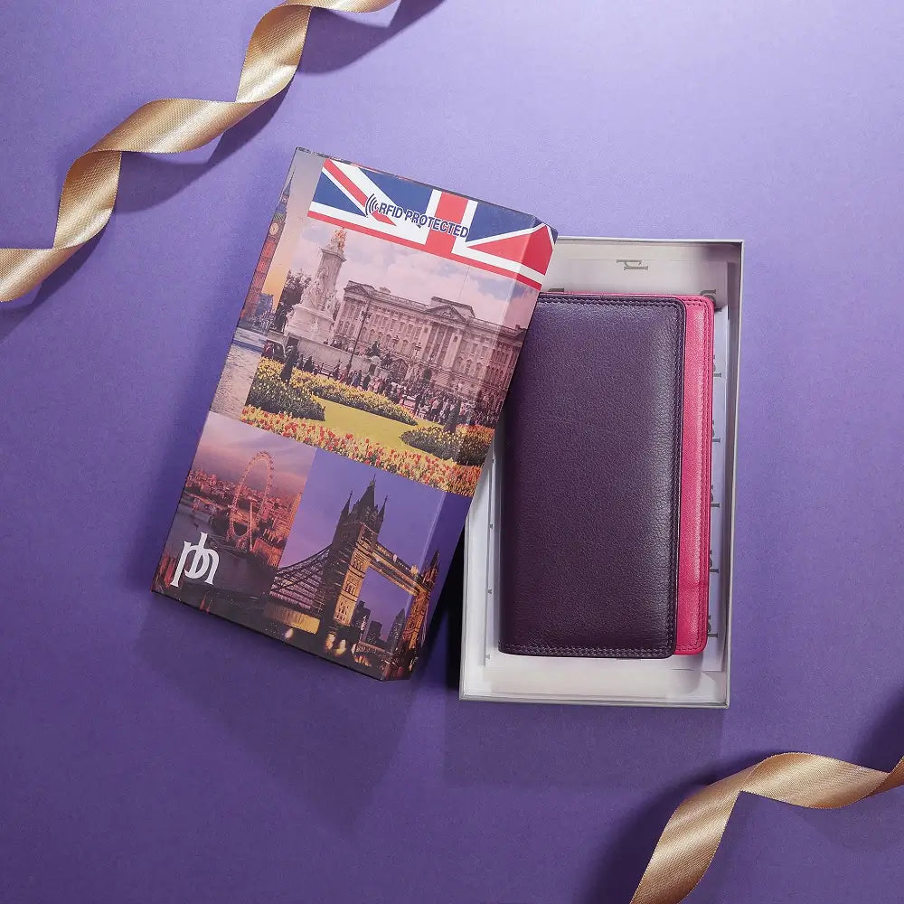Purple wallet with pink interior in a box, featuring a travel-themed passport cover on a purple background.