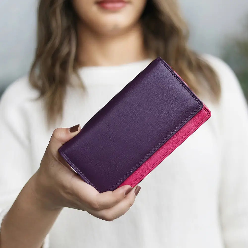 Person holding a two-tone leather wallet with a purple top and pink bottom.