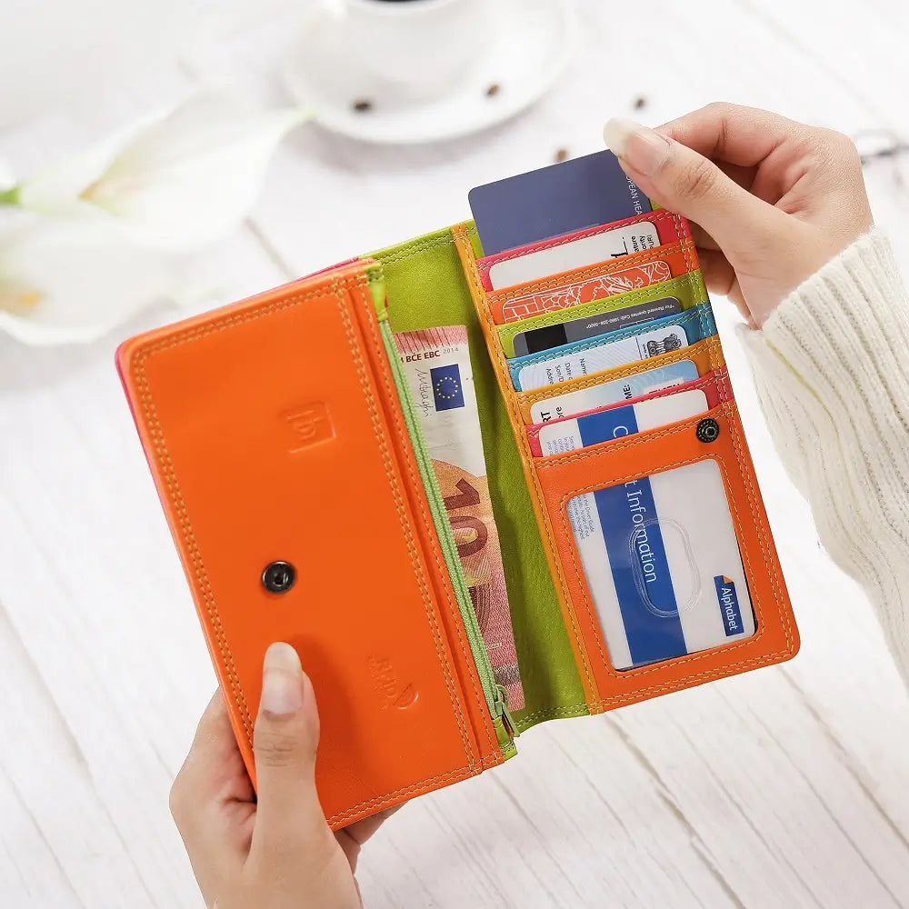 Person holding a Green wallet with cards and money next to a cup of coffee on a wooden table.