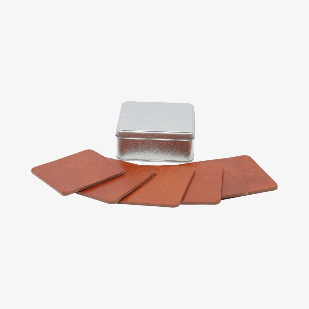 Tan leather coasters for coffee table with a metal tin on a white background