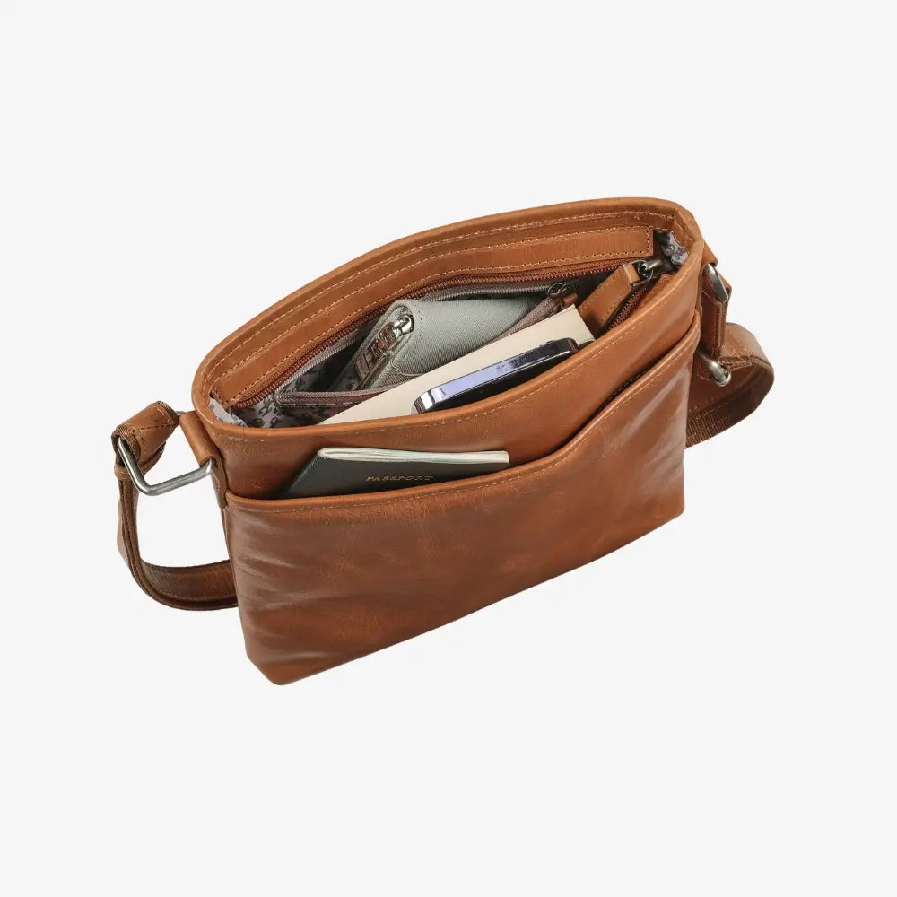 Tan leather crossbody bag with items inside on a white background