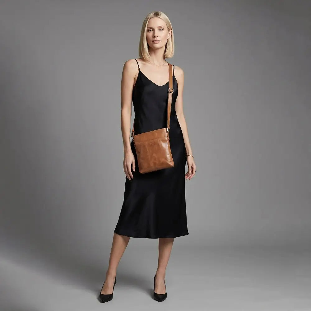 Woman holding a tan leather bag against a gray background