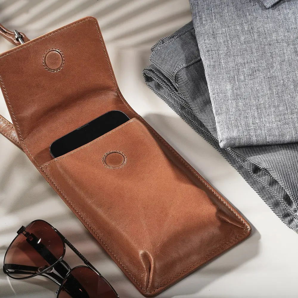 Tan leather wallet with sunglasses on a light gray background
