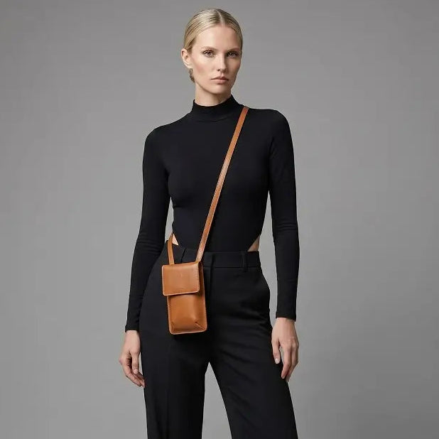 Woman wearing a black outfit with a Tan leather bag on a gray background