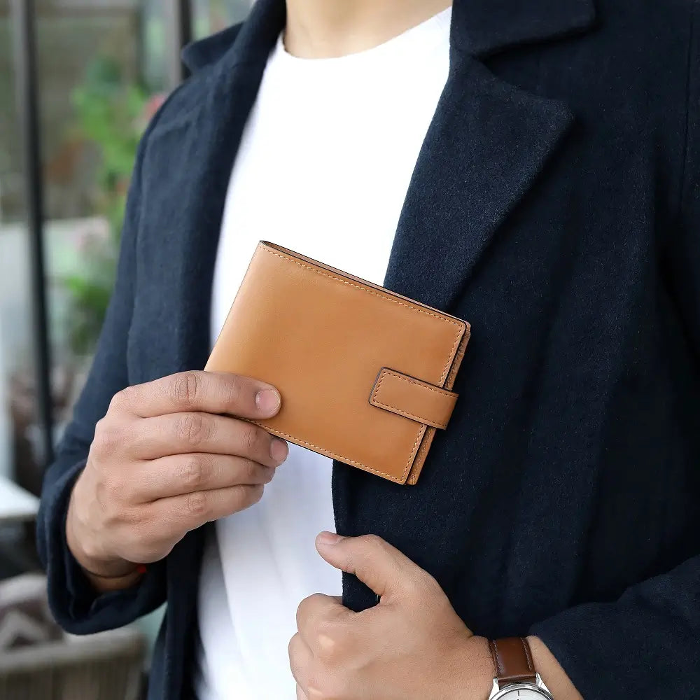 Person holding a tan leather wallet with a blurred background