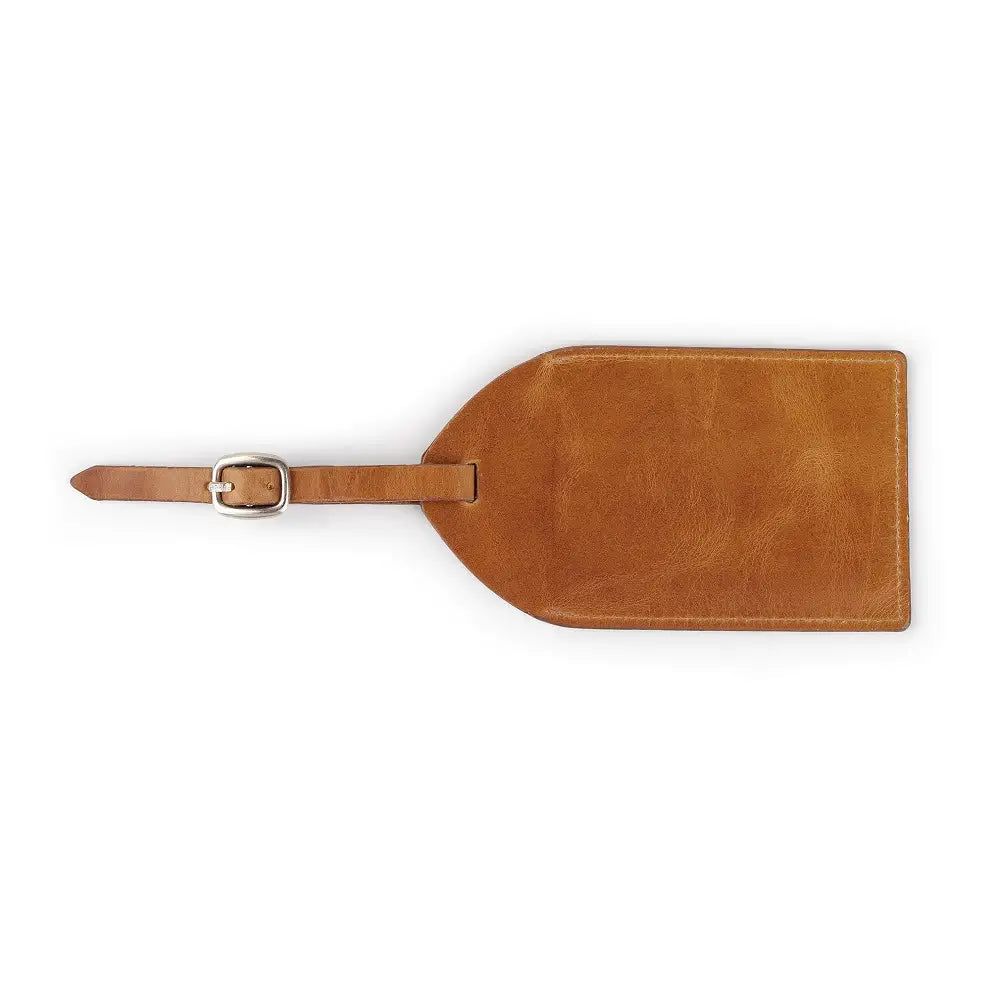 Top view of tan full-grain leather luggage tag showing ID window, flap cover, and buckle strap.