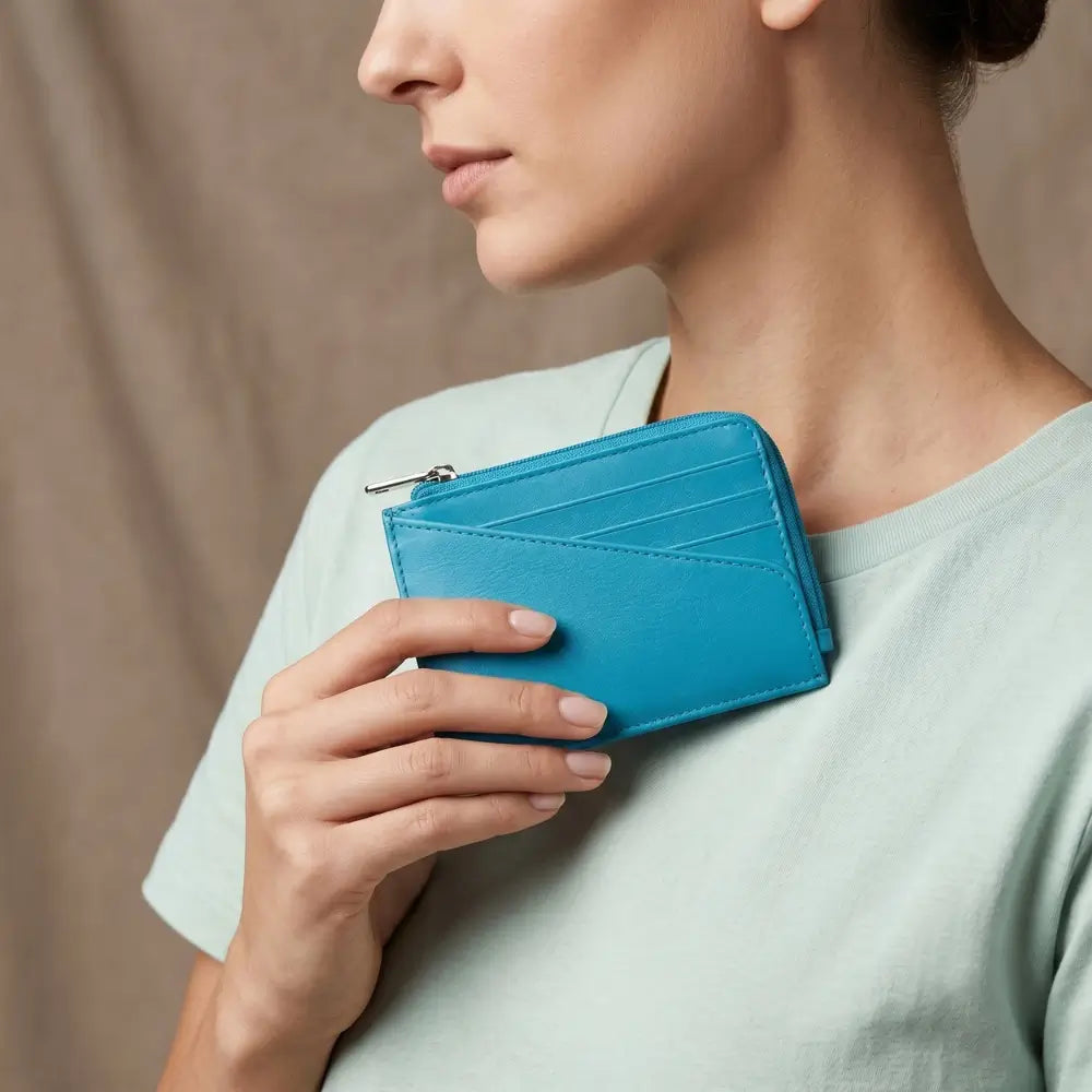Person holding a turquoise wallet against a neutral background