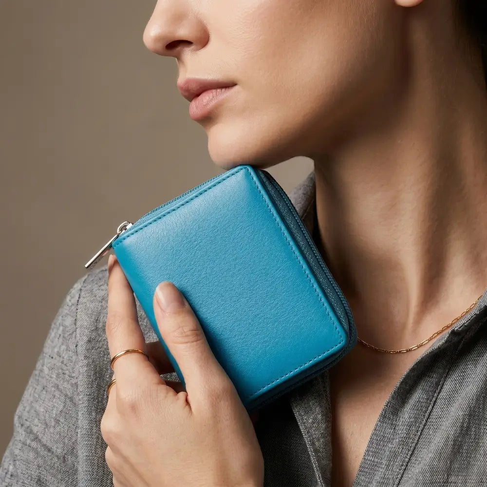 Person holding a turquoise wallet against a neutral background