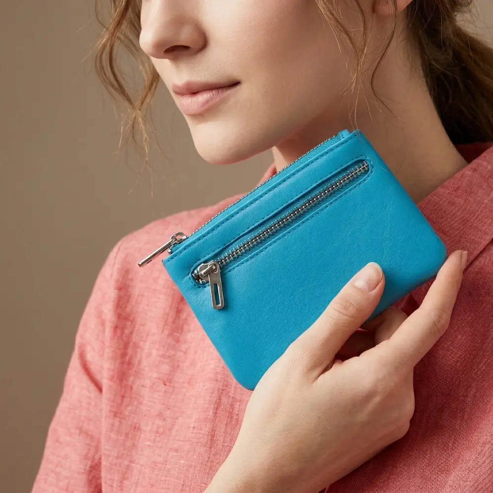 Person holding a turquoise wallet against a neutral background