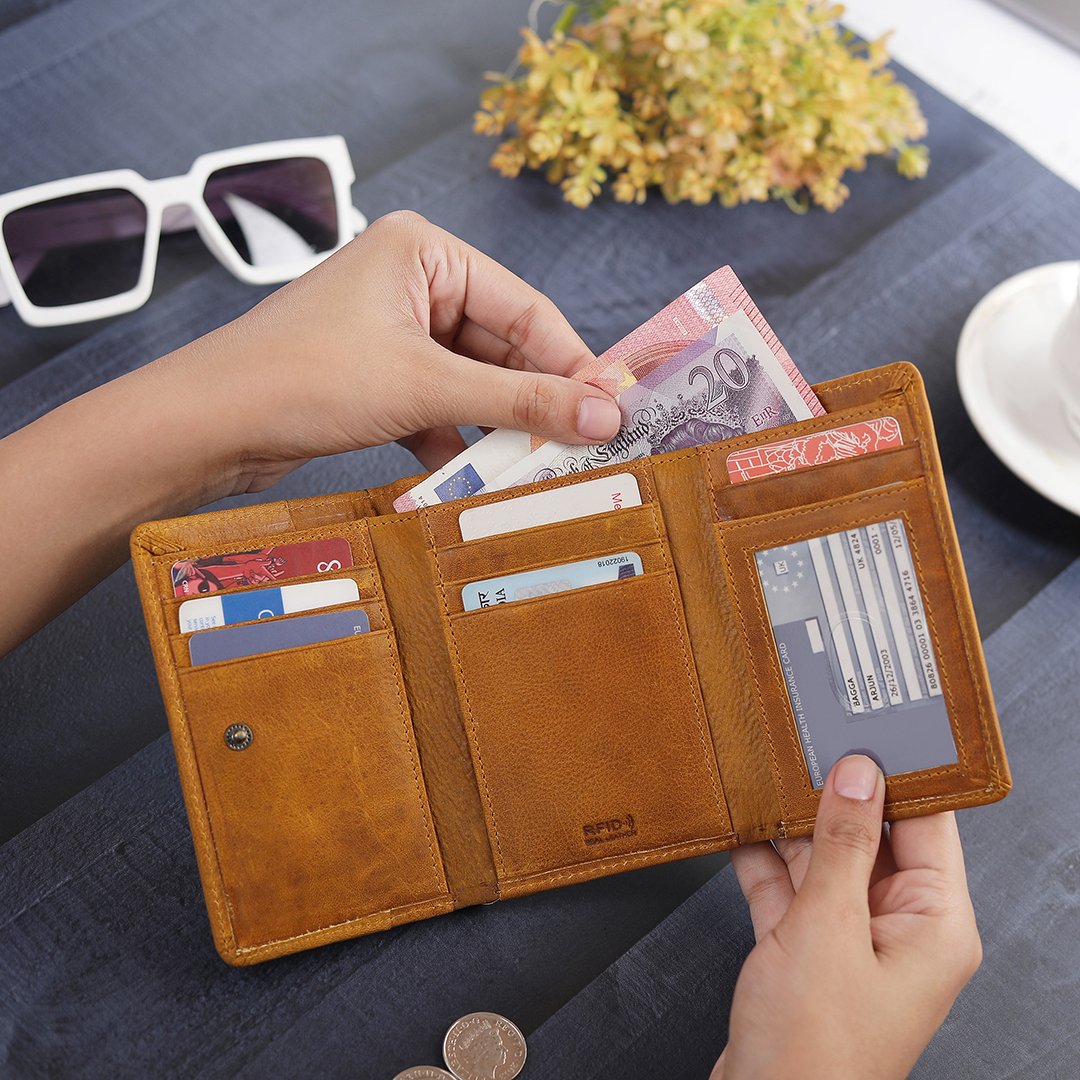 A person placing cash inside the yellow trifold wallet, showcasing its spacious bill compartment and efficient organization of cards.