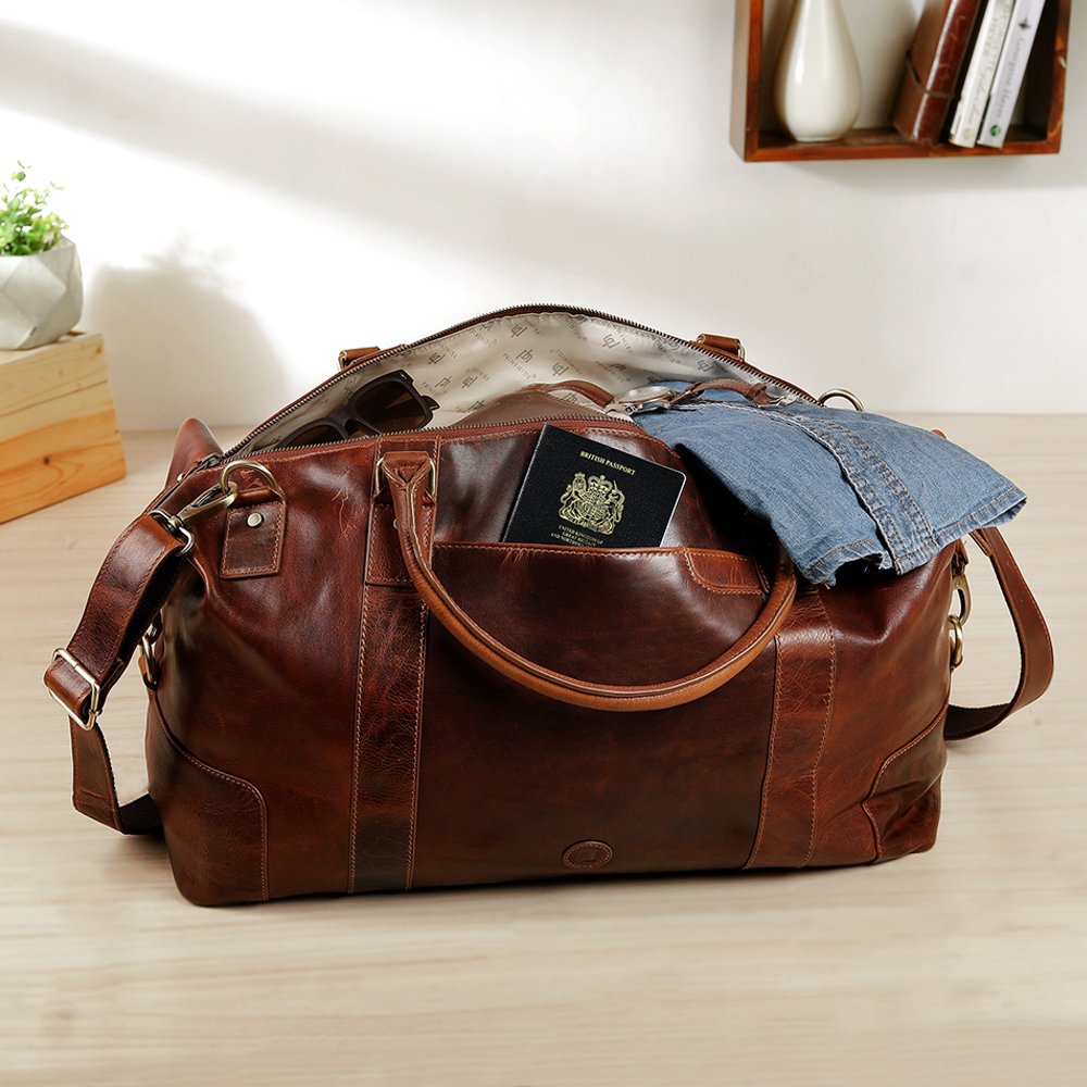 Orion tan leather holdall travel bag by Primehide open and packed with clothes, full-grain leather with brass fittings.