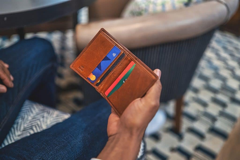 a man is holding a brown leather credit card wallet. the wallet is embossed with RFID