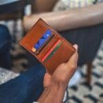 a man is holding a brown leather credit card wallet. the wallet is embossed with RFID