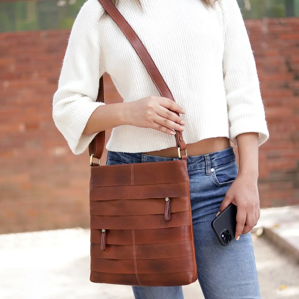 Woman wearing the Boho Layered Leather Bag - Ridgeback as a crossbody bag, showcasing its rustic brown leather design with brass-toned hardware and artisanal layered panel details.