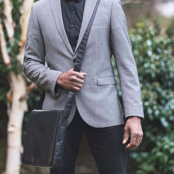 A man in a suit holding a Black leather man bag.