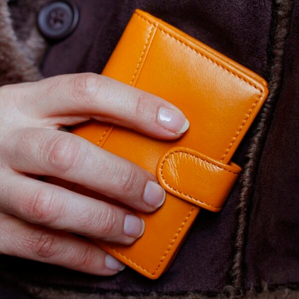 a woman is holding a deep yellow card wallet