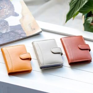 three small leather wallet are on a table. they have detailed stitching