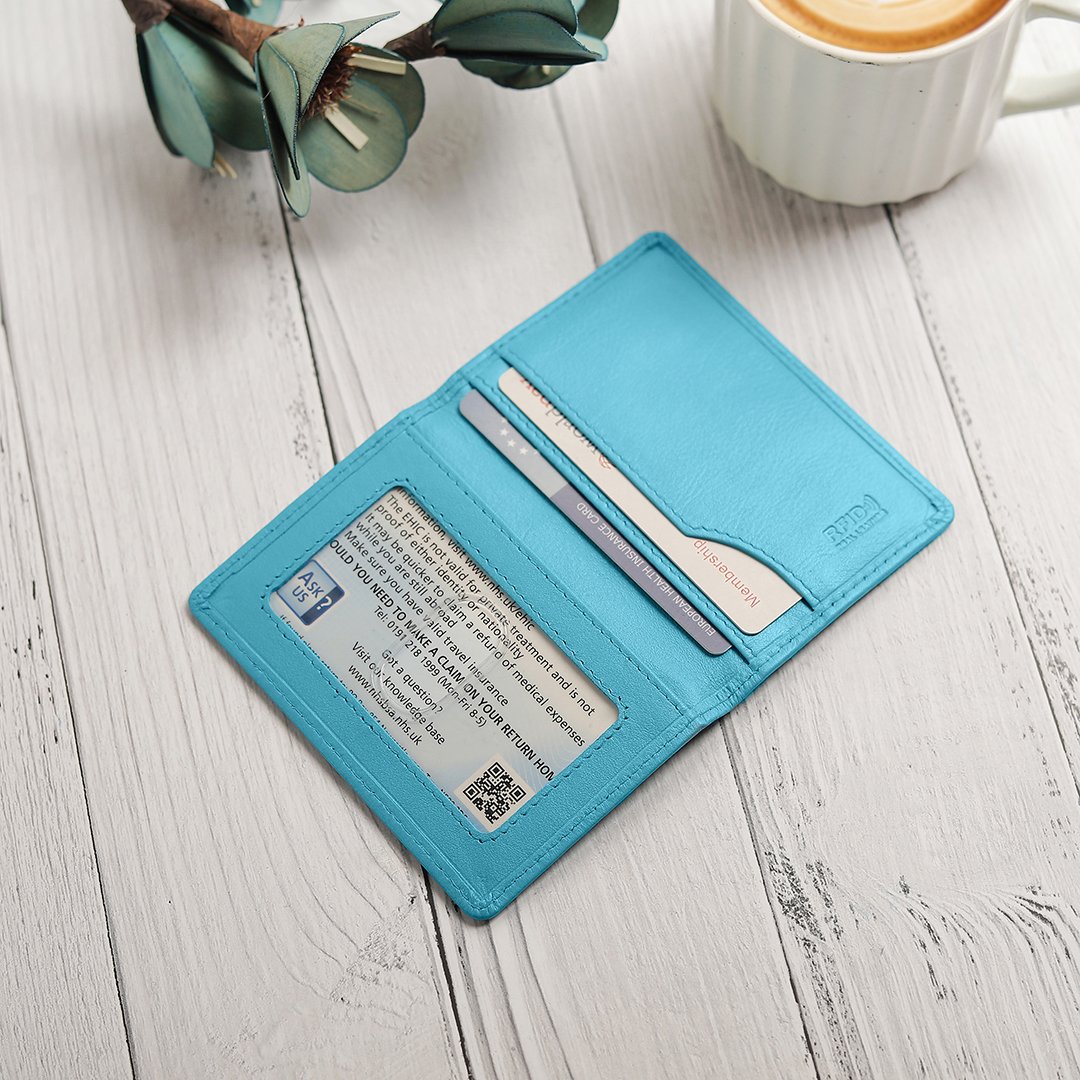 The turquoise leather travel card holder opened, showing multiple card slots filled with cards and a transparent window for an ID or travel pass.