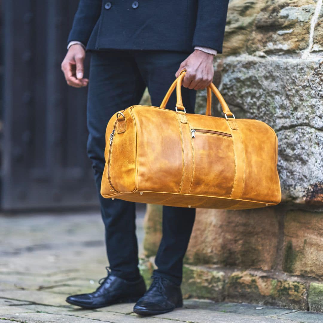 a man is carrying a luxury leather duffle bag