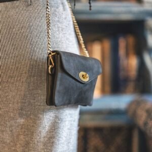 a small black leather bag with a brass chain