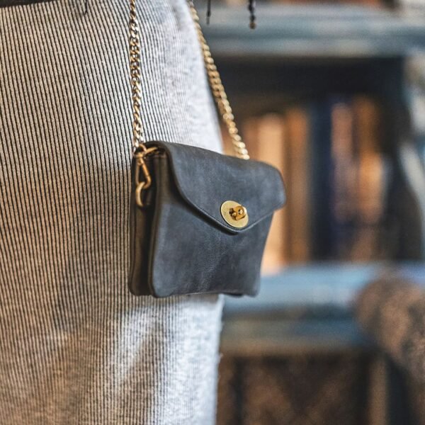 a small black leather bag with a brass chain