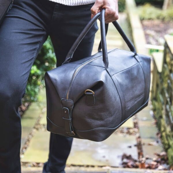 Stylish man confidently carries a sleek black leather holdall, embodying sophistication and functionality