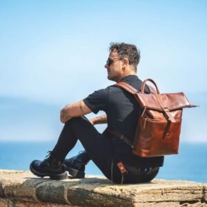 brown leather roll top backpack worn by a stylish man