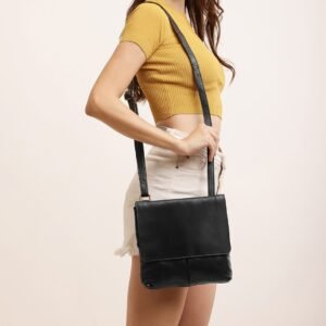 A person wearing a yellow top and white shorts models the black PRIMEHIDE crossbody organiser bag made of real leather.