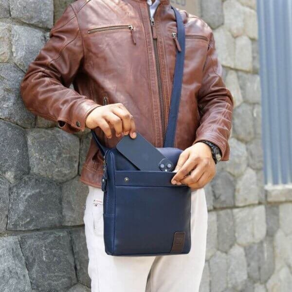 Man using navy leather messenger bag with front slip pocket – unisex crossbody bag ideal for travel or everyday use.